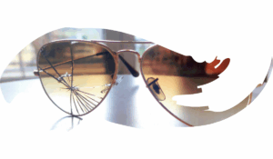 Sunglasses on a table. The right lens is broken. Light shines through the broken lens.